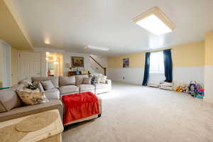 Carpeted living room with wainscoting and stairway