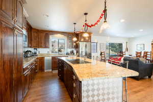 Kitchen with a center island with sink, appliances with stainless steel finishes, a breakfast bar, wood finished floors, and a sink