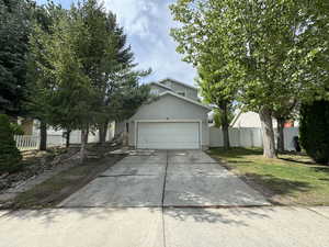 View of property hidden behind natural elements with a garage