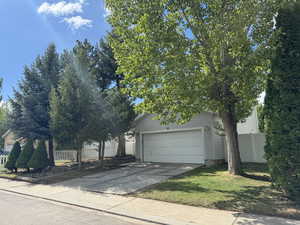 View of property hidden behind natural elements with a garage