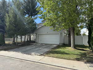 View of property hidden behind natural elements with a front yard