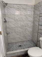 Bathroom featuring tiled shower and toilet