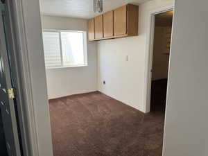 Unfurnished room with a textured ceiling and dark colored carpet