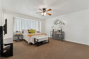 Bedroom with baseboards, dark carpet, and ceiling fan