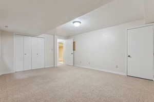 Unfurnished bedroom with light carpet, baseboards, visible vents, and a textured ceiling