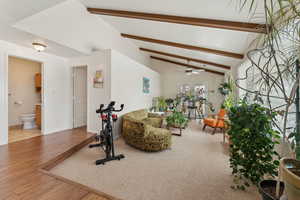 Exercise area with a ceiling fan, vaulted ceiling, baseboards, and wood finished floors