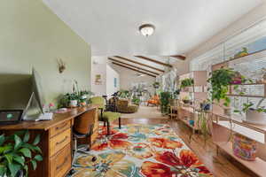 Interior space with light wood-style floors, ceiling fan, and lofted ceiling with beams