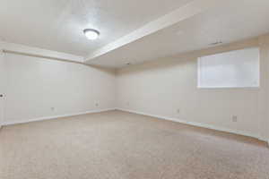 Spare room featuring a textured ceiling, carpet flooring, visible vents, and baseboards