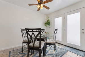 Dining space with light tile patterned floors, a ceiling fan, and baseboards