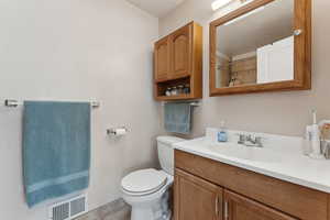 Bathroom with tile patterned floors, visible vents, toilet, vanity, and walk in shower