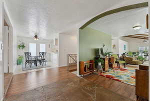 Interior space with arched walkways, ceiling fan, a textured ceiling, and light wood-style floors