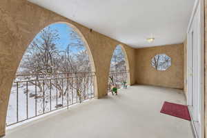 Snow covered patio featuring a balcony