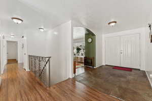 Entrance foyer featuring arched walkways, a textured ceiling, dark wood finished floors, and baseboards