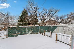 Yard layered in snow with a gate and fence