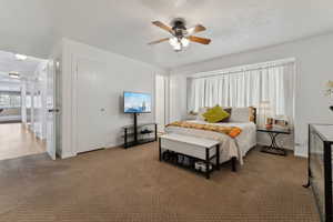 Bedroom featuring carpet floors, a textured ceiling, baseboards, and a ceiling fan