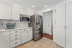 Kitchen featuring light tile patterned floors, light countertops, appliances with stainless steel finishes, and white cabinetry