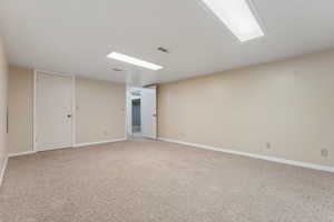 Empty room with carpet floors, visible vents, and baseboards