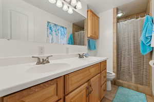 Full bathroom featuring double vanity, a sink, toilet, and tile patterned floors