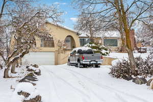 View of front of home with a chimney, an attached garage, and stucco siding