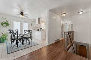 Dining room featuring light wood finished floors, visible vents, ceiling fan, a textured ceiling, and baseboards