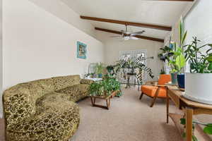 Living room with lofted ceiling with beams, a ceiling fan, and carpet flooring