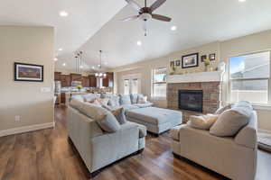 Living room with vaulted ceiling, a fireplace, dark wood-style floors, and baseboards