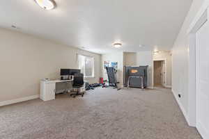 Home office featuring light carpet, a textured ceiling, visible vents, and baseboards