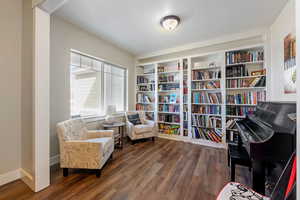 Living area featuring baseboards, dark wood finished floors, and a textured ceiling