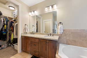 Bathroom featuring double vanity, tile patterned flooring, a walk in closet, and a sink