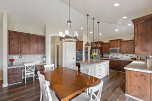 Kitchen featuring pendant lighting, stainless steel appliances, a kitchen island, and light stone countertops