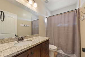 Bathroom with toilet, visible vents, a shower with shower curtain, and vanity