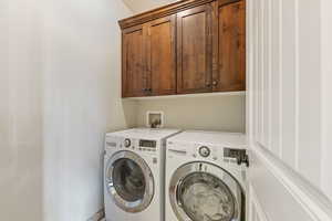 Washroom featuring cabinet space and separate washer and dryer