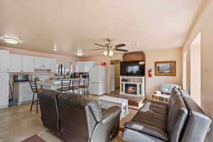 Living room featuring a ceiling fan and a glass covered fireplace