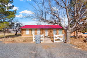 View of front of house with brick siding, metal roof, and fence