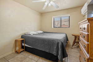 Bedroom with light tile patterned flooring, ceiling fan, and baseboards