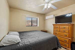 Bedroom with a ceiling fan and a wall mounted air conditioner