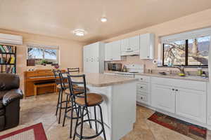 Kitchen featuring electric stove, light countertops, white cabinetry, a sink, and under cabinet range hood