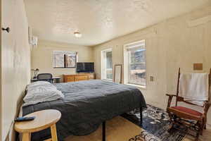 Bedroom with a wall mounted air conditioner, baseboards, and a textured wall