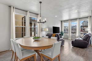 Dining room with a chandelier, a textured ceiling, baseboards, and wood finished floors