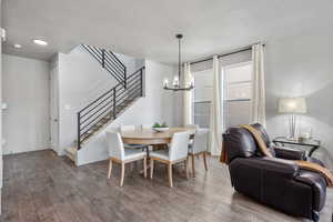 Dining space featuring a textured ceiling, stairway, wood finished floors, and an inviting chandelier