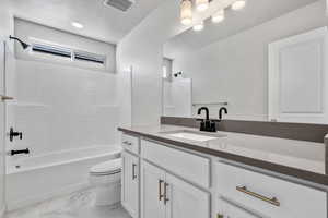 Bathroom featuring a textured ceiling, shower / tub combination, toilet, visible vents, and marble finish floor