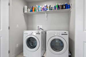 Clothes washing area featuring laundry area, baseboards, marble finish floor, and separate washer and dryer