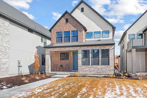 View of front of house featuring a shingled roof, stone siding, and brick siding