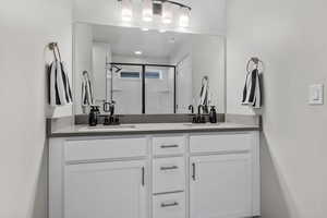 Bathroom featuring double vanity, a stall shower, and a sink