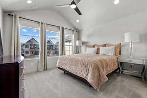 Bedroom with lofted ceiling, light carpet, visible vents, and a ceiling fan