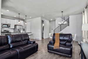 Living area featuring recessed lighting, visible vents, wood finished floors, baseboards, and stairs