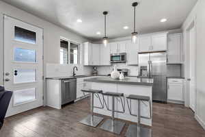 Kitchen with dark countertops, a kitchen island, appliances with stainless steel finishes, and a breakfast bar area