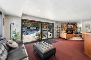 Carpeted living area featuring recessed lighting, a textured ceiling, and a stone fireplace