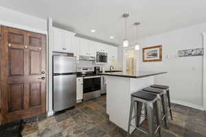 Kitchen featuring appliances with stainless steel finishes, stone tile flooring, and white cabinetry