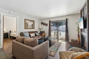 Living area with dark wood-type flooring, a fireplace, and baseboards